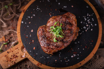 Grilled juicy steak on a wooden board with pepper and salt 