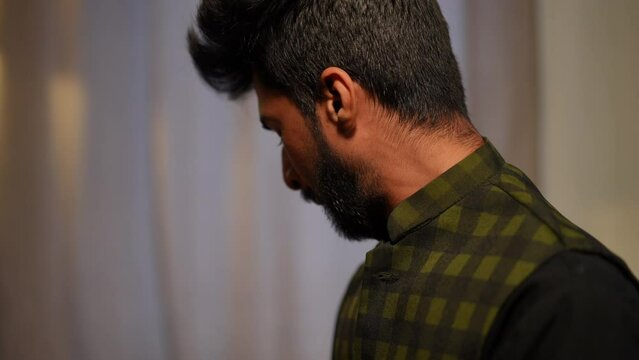 Side view Muslim man touching face and spitting to both sides indoors. Concentrated handsome Middle Eastern male believer praying on Ramadan