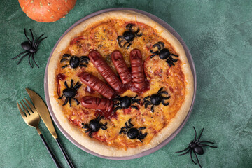Halloween pizza with sausage fingers and spiders, Creative idea for Halloween on green background