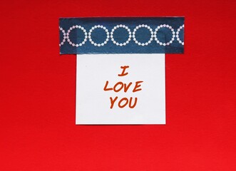 Note stick on red background with handwritten text I LOVE YOU, concept of self talk to remind...