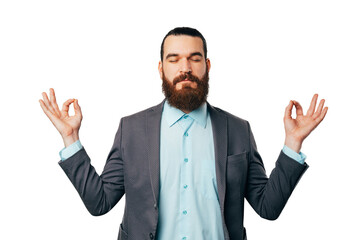 Relaxed bearded man wearing a jacket is staying in mudra pose in a studio over white background.