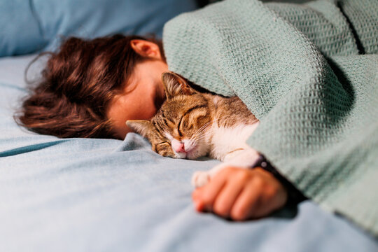 boy falls asleep and hugs his cat, who sleeps with him under the covers. children and pets. the cat sleeps with the baby.