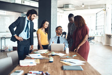 The world online aids their team efforts. a group of businesspeople working together on a laptop in an office.