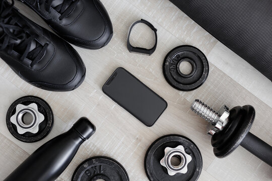 Flat lay of mobile phone and sport equipment on wooden background