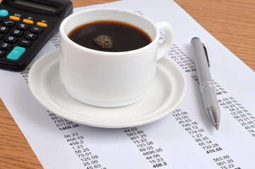 Tasse de café et stylo sur un listing de chiffres
