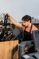 man in apron using professional print plotter while working in print center.