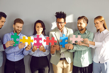 Young business team connecting jigsaw parts. Group of happy, smiling diverse multiracial people...