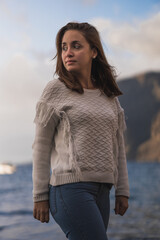 Caucasian woman with brown hair and white shirt on the beach at sunset.