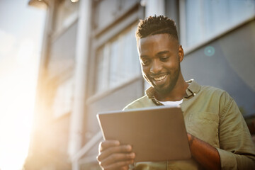 Hes always got his trusty tablet in tow. a handsome young man using his digital tablet outside.