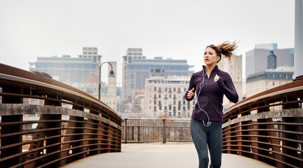 The road to fitness is long and rewarding. an attractive young woman listening to music while...