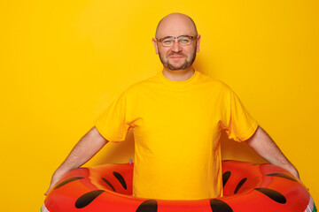Man holding inflatable swim ring on yellow colored background