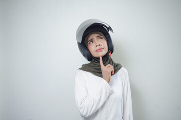 Young asian muslim woman smiling and thinking using motorcycle helmet isolated on white background
