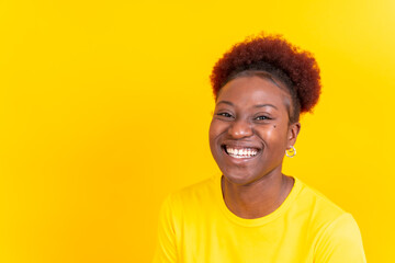 Young african american woman isolated on a yellow background smiling and laughing, studio shoot