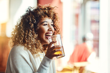Shes having an awesome time. a young woman enjoying a drink at a bar.