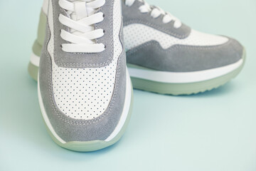 Sneakers for everyday use on a pale green background. Sneaker toe with suede and white leather with...