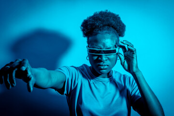 Young black woman enjoying the future. Studio photo in dark studio with blue neon light. science fiction portrait