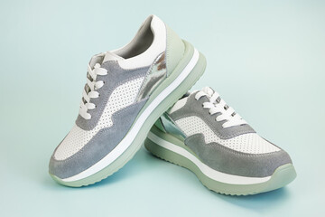 Sneakers for everyday use on a pale green background. Pair of unisex leather athletic boots with...