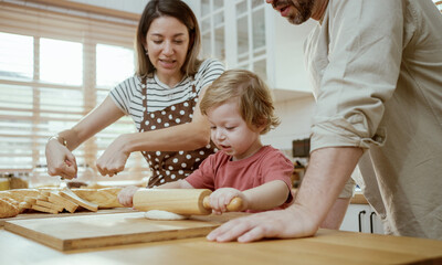 Father and mother teaching baby son kneading dough on kitchen counter at home. Parents and boy kid enjoy and fun indoors activity cooking together.