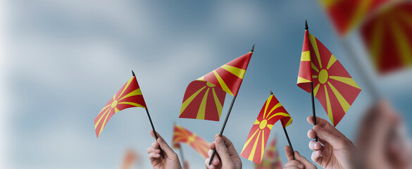 A group of people holding small flags of the Macedonia in their hands