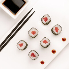 Sushi plate on white background, rolls set with tuna on white background from above. Top view of traditional japanese cuisine. Asian food with chopsticks design.