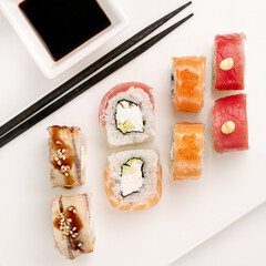 Sushi plate on white background, rolls set mix on white background from above. Top view of traditional japanese cuisine. Asian food with chopsticks design.