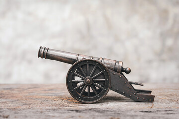 Ancient cannon on steel wheels with wall background retro style.