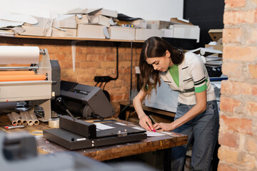 busy typographer holding knife near paper while working in print center.