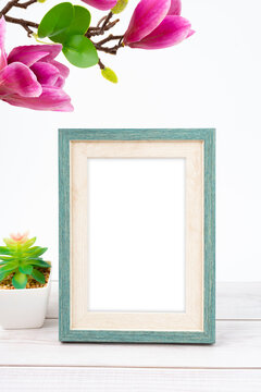 The Blank picture frame with magnolia flower on white floor with copy space and clipping path for the inside.