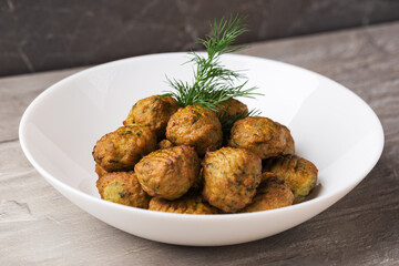 A view on a plate with fish balls with spinach on a white plate on stone table. Isometric style. Healthy eating concept. Selective focus.