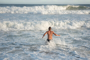 Back view of a man running on the beach. Sports lifestyle.