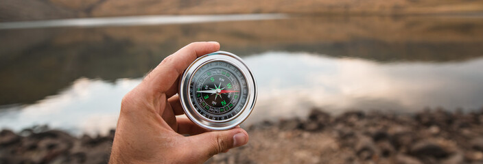 man holding compass on lake background