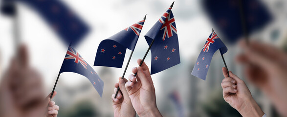 A group of people holding small flags of the New Zealand in their hands