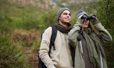 Fototapeta premium Taking a closer look as they hike to the top. A young couple taking in all the scenary while enjoying a mountain hike.