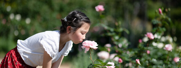 薔薇の香りを嗅ぐ少女