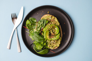 Bruschetta with avocado on a black plate.