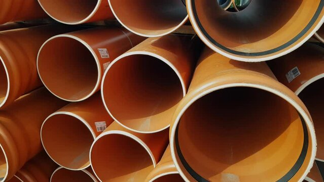 A large pile of  plastic orange sewage pipes used in the city sewage system