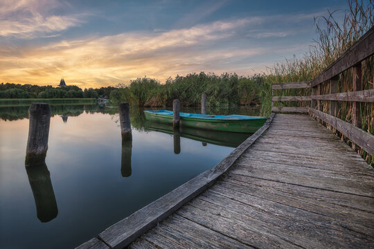 Lonely Boat at The Wooden Pier on Tisza Lake at Sunset.
