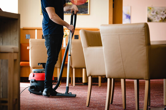 Angestellte Reinigungskraft saugt den Teppich