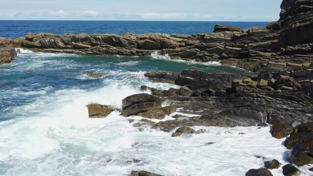 Waves crashing against oddly shaped rock formations off the north coast of Asturias, Spain.
