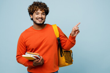 Young teen Indian boy student wear casual clothes backpack bag hold books point index finger aside...