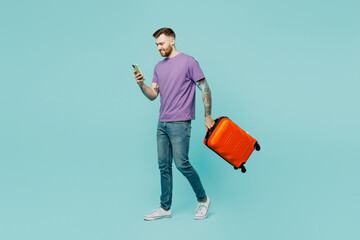 Traveler man wear casual clothes hold suitcase mobile cell phone isolated on plain pastel green color background. Tourist travel abroad in free spare time rest getaway Air flight trip journey concept