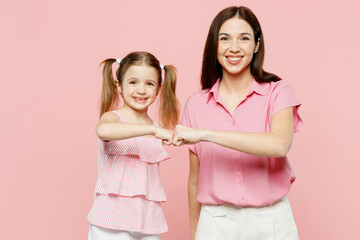 Happy smiling satisfied woman wearing casual clothes with child kid girl 6-7 years old. Mother daughter give fist bump look camera isolated on plain pastel pink background. Family parent day concept.