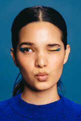 Female with bold eyeliner making a face, winking and pouting her lips