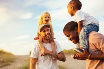 Two fathers giving piggyback ride to daughters (2-3)