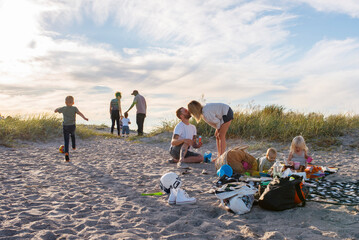 Two families picnicking together with children (6-11 months, 2-3, 4-5) on beach