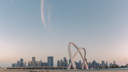 Doha skyline at sunset of light blue and yellow colored sky, Middle east, Qatar, rainbow roundabout 