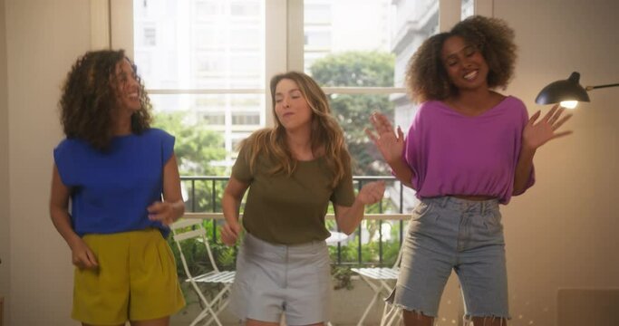 Group of Multiethnic Female Friends Having Fun and Dancing to Music at Home in Cozy Sunny Living Room. Active, Young Girls Enjoying Summer Vacation Together, Laughing and Singing Along. Slow Motion