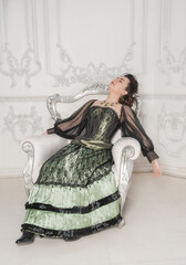 Beautiful young woman wearing medieval vintage Victorian Style dress passed out in the armchair