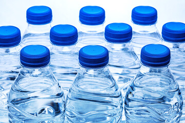 pile of half litre plastic water bottles with blue cap