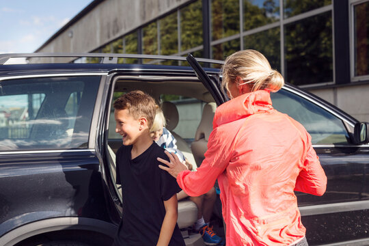 Mother with sons (10-11, 12-13) getting out of car